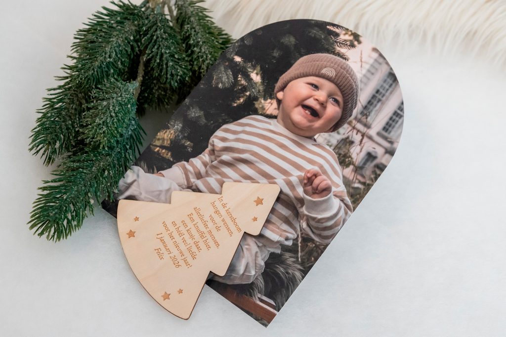 Nieuwjaarsbrief in stolpvorm met foto en houten magneet met tekst die op kaart wordt bevestigd.