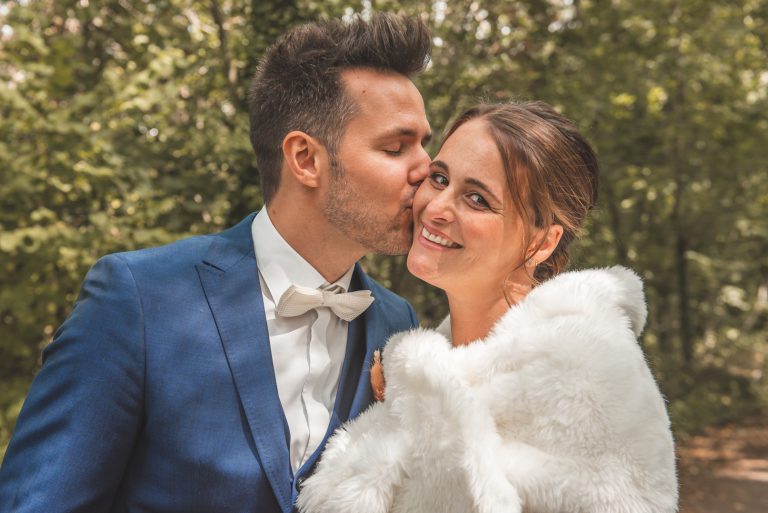 Getrouwd koppel in trouwkleding met blauw kostuum en witte bolero in bont