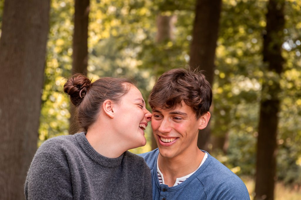 Een jonge vrouw met haar vriend die aan het lachen zijn in het bos.